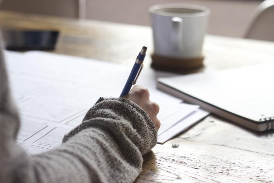 A hand writing notes with a pen